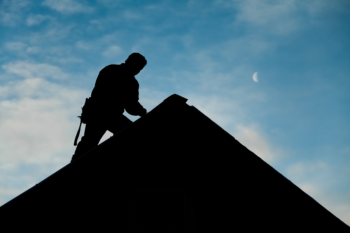 Silhouette of an inspector doing a home inspection on the roof